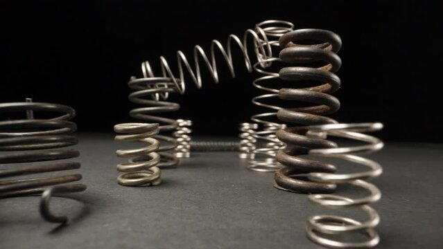 A set of metal springs are on the table, the camera flies through them. Dolly slider extreme close-up. Laowa Probe
