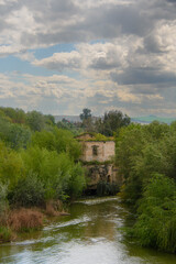 Fototapeta premium Old building on the Guadalvidir river seen from the old Roman bridge in Cordoba, Andalusia, Spain