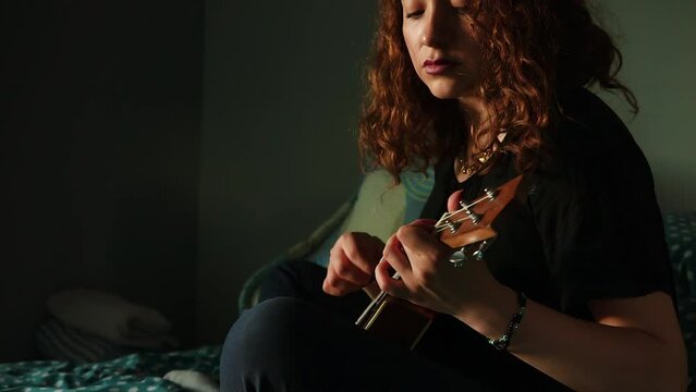 Mujer tocando el ukulele y cantando en su habitaci&oacute;n. Concepto de musica.