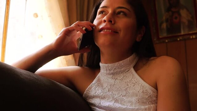 Mujer habla por tel&eacute;fono sonriente en su casa. Concepto de hogar y tecnolog&iacute;a.