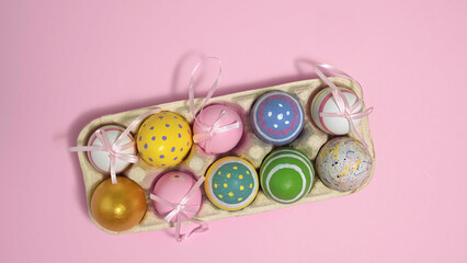 Colorful Easter eggs In A Cardboard Box on pink background. Eggs In A Paper Egg Container. Multicolored egg for Happy easter. Hello spring and Happy Easter holiday concept. Top View