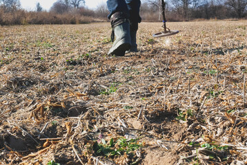 Man with metal detector is moving from side to side on the field for gold and silver metal seeking....