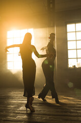 Couple of two professional ballroom dancers is dancing on loft studio. Beautiful art performance...