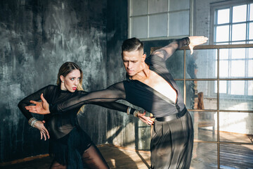 Couple of two professional ballroom dancers is dancing on loft studio. Beautiful art performance...