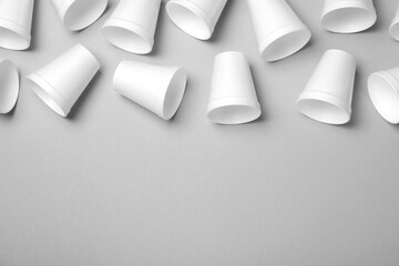 Many styrofoam cups on light grey background, flat lay. Space for text
