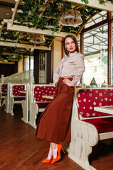 A beautiful girl showing fashionable clothes against the backdrop of the restaurant scenery. Clothes for the showroom