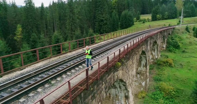 Aerial shot construction worker on railways. Work on railway. Old railway bridge over a river. Engineer work on railway. Engineer walking and check track work on railways. People walk on railway