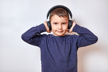A handsome boy listens to music in headphones with pleasure and a smile.