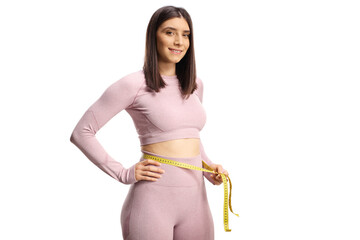 Fit woman in sportswear measuring her waist and smiling at camera