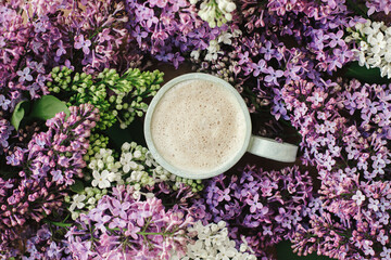Fototapeta Stylish composition of lilac flowers and warm cup of coffee, flat lay. Colorful lilac branches and coffee with creamy foam, good morning concept. Spring morning still life obraz