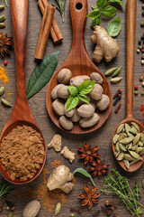 Different herbs and spices with spoons on wooden table, flat lay