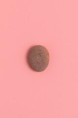 Oval shaped stone on a pink background. Fake Easter egg.