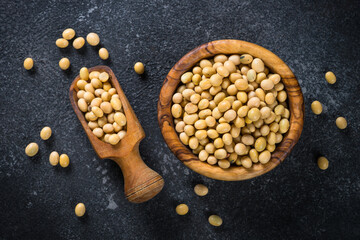 Soy is a source of plant based protein. Vegan food. Soya beans in the wooden bowl at black stone table.