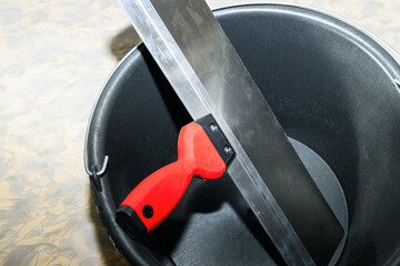 Clean spatula (trowel ) in an empty bucket close-up. Construction finishing works