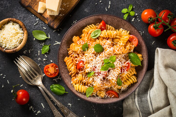 Italian pasta alla arrabiata with basil and parmesan on dark table. Top view image with space for design.