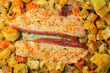 Raw duck breast with vegetables prepared on a metal baking tray