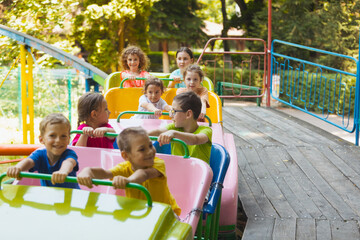 Fototapeta na wymiar The happy kids on a roller coaster in the amusement park