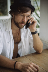 A young handsome man in a casual look calls on the phone, talks on the phone.