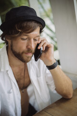 A young handsome man in a casual look calls on the phone, talks on the phone.