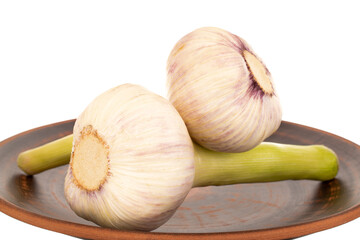 Two heads of early garlic on a ceramic plate, macro, isolated on a white background.