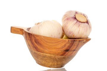 Two heads of early garlic in a wooden cup, close-up, isolated on a white background.