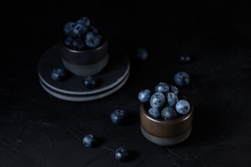 Fresh blueberries in a gray ceramic bowl on a black background. Close-up.