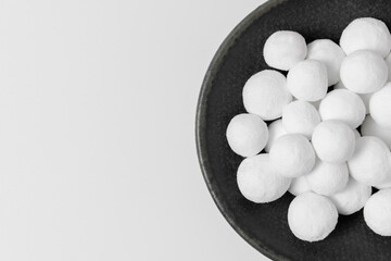 White sugar balls on a gray ceramic plate isolated on a white background. Close-up, top view, copy space.