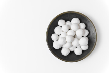 Sweet white sugar balls on a gray ceramic plate isolated on a white background. Close-up, top view, copy space.