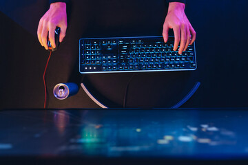 Top view of hands of pro cyber sport gamer playing shooter game with RGB keyboard and computer mouse. Gamer's hands, professional gaming setup and energy drink. Close up. Neon color. Cyber sport © Arsenii