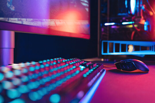 Close-up of professional gaming setup laying on desktop in neon lights. Gaming studio equipment are ready for online competition, tournament, e-sport event. Selective focus. Cyber sport, e-sport