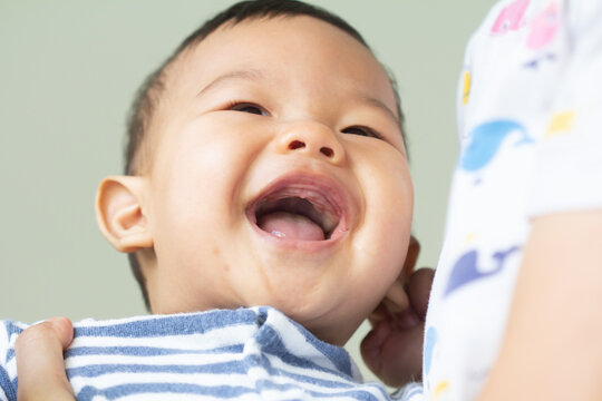 Baby boy smiling and showing his two teeth. Indoors, close up with copy space