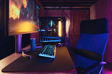 Cyber sport. Professional gaming PC setup and full RGB light inside. Gaming desktop, monitor, keyboard, gaming computer mouse, armchair. Neon coloured room of pro gamer, place for playing video games
