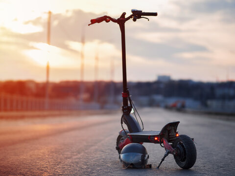Powerful modern urban electric scooter on the road with sunset view. Helmet with visor.
