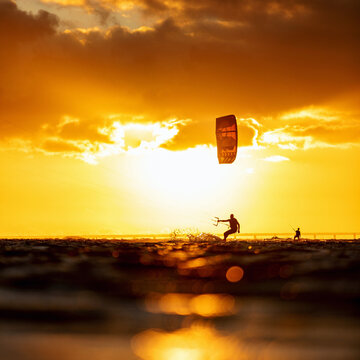 Beautiful view of a man kitesurfing at scenic sunset