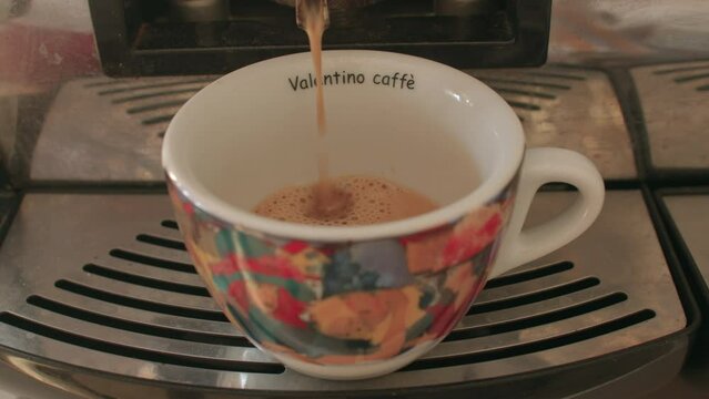 08.10.2021 Borgagne, Puglia, Italy. Pouring coffee into the coffee machine. Using a mug with a print. A jet of hot drink flows. Looking for vigor in a stimulant.