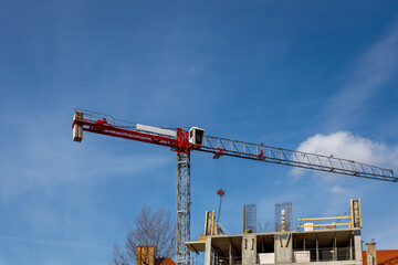 dźwig w czerwonym kolorze na niebieskim niebie w trakcie budowy budynków mieszkalnych. Wzrost zapotrzebowania na mieszkania w Europie.