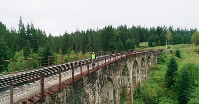 Aerial shot construction worker on railways. Engineer work on railway. An Engineer walking on railways with inspection railroad under maintenance period. Old railway bridge over a river