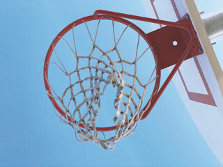 Low angle shot of a red basketball hoop on a blue sky background