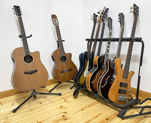 different electric guitars, bass guitars, acoustic and classical guitars on stand