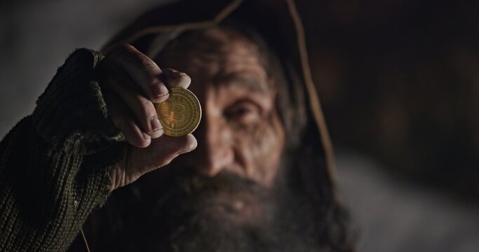 Crafty elderly man checking golden coin