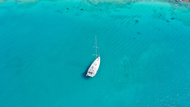 Aerial drone photo of beautiful sail boat anchored in Aegean island paradise bay with turquoise sea