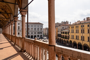 The scenic view on Piazza delle Erbe from the loggia which is the external balcony of Palazzo della Ragione in Padua, Veneto, Italy, Europe. Light beams on beautiful colonnade with column architecture