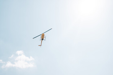 Fototapeta na wymiar Yellow helicopter flying in the blue sky