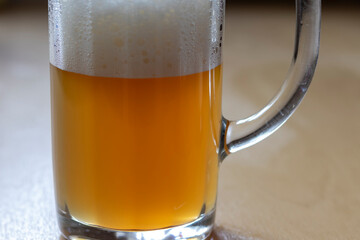 Cold beer with foam in a mug, on the table.