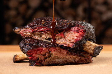 Closeup shot of a sauce pouring on smoked pork ribs on a wooden board