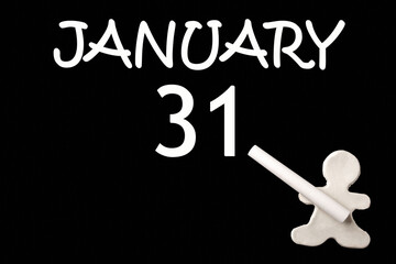 A small white plasticine man writing the date 31 January on a black board. Business concept. Education concept.