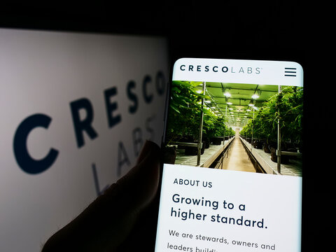 Stuttgart, Germany - 03-28-2022: Person holding cellphone with webpage of American cannabis company Cresco Labs Inc. on screen in front of logo. Focus on center of phone display.
