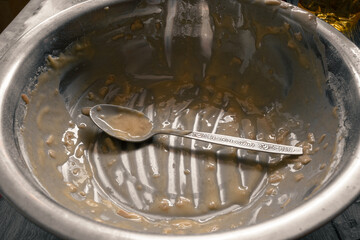 A metal bowl with a spoon after kneading the dough. Dirty empty bowl