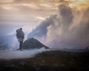 Rear view of a tourist with a backpack watching a beautiful view of the volcano