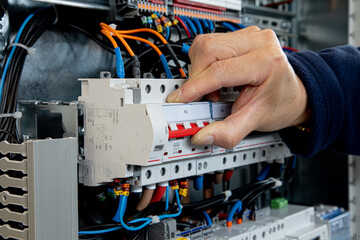 Closeup of the hand switching on a circuit breaker to power an electrical installation